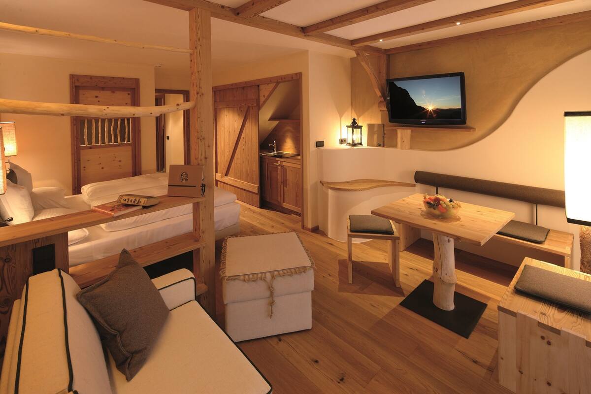 Una habitación acogedora con una cama, una mesa de madera y un televisor montado en la pared.