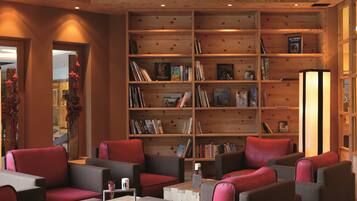 Un rincón acogedor para leer con estanterías, asientos cómodos y un interior de madera cálida.