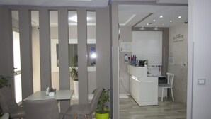 Habitación de hotel moderna con comedor, kitchenette y vista al pasillo.