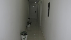 Un pasillo estrecho y bien iluminado con paredes blancas y piso brillante, que conduce a una puerta al final.