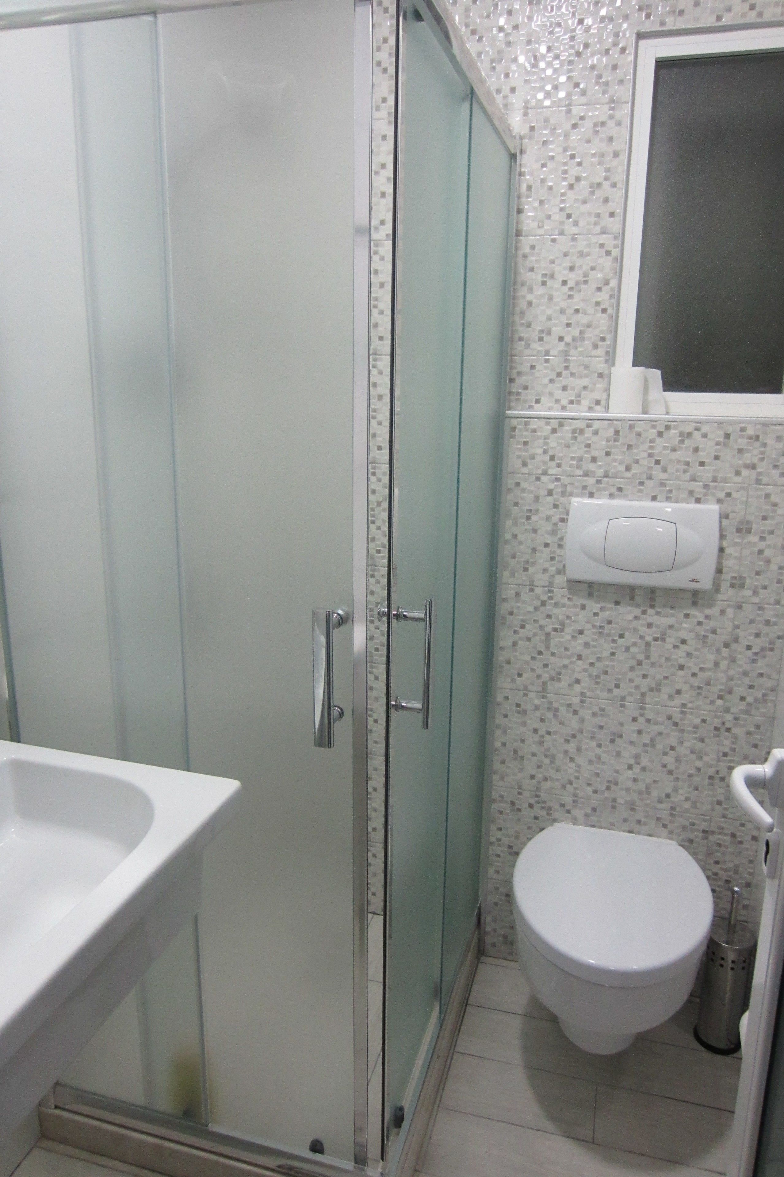 A bathroom with a glass shower enclosure, a white toilet, and a sink.