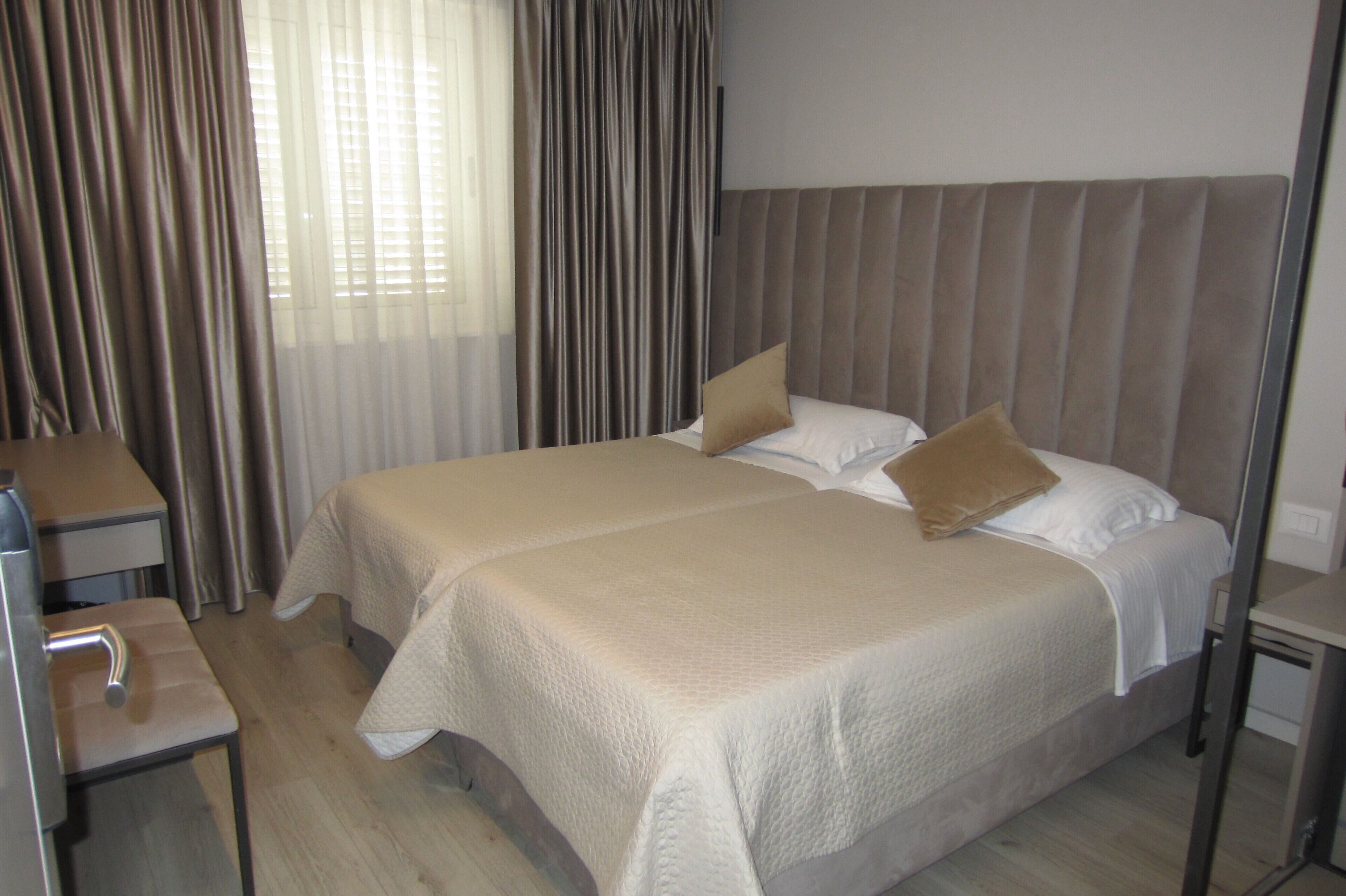 Een hotelkamer met een groot bed, twee nachtkastjes, een bureau en een stoel.