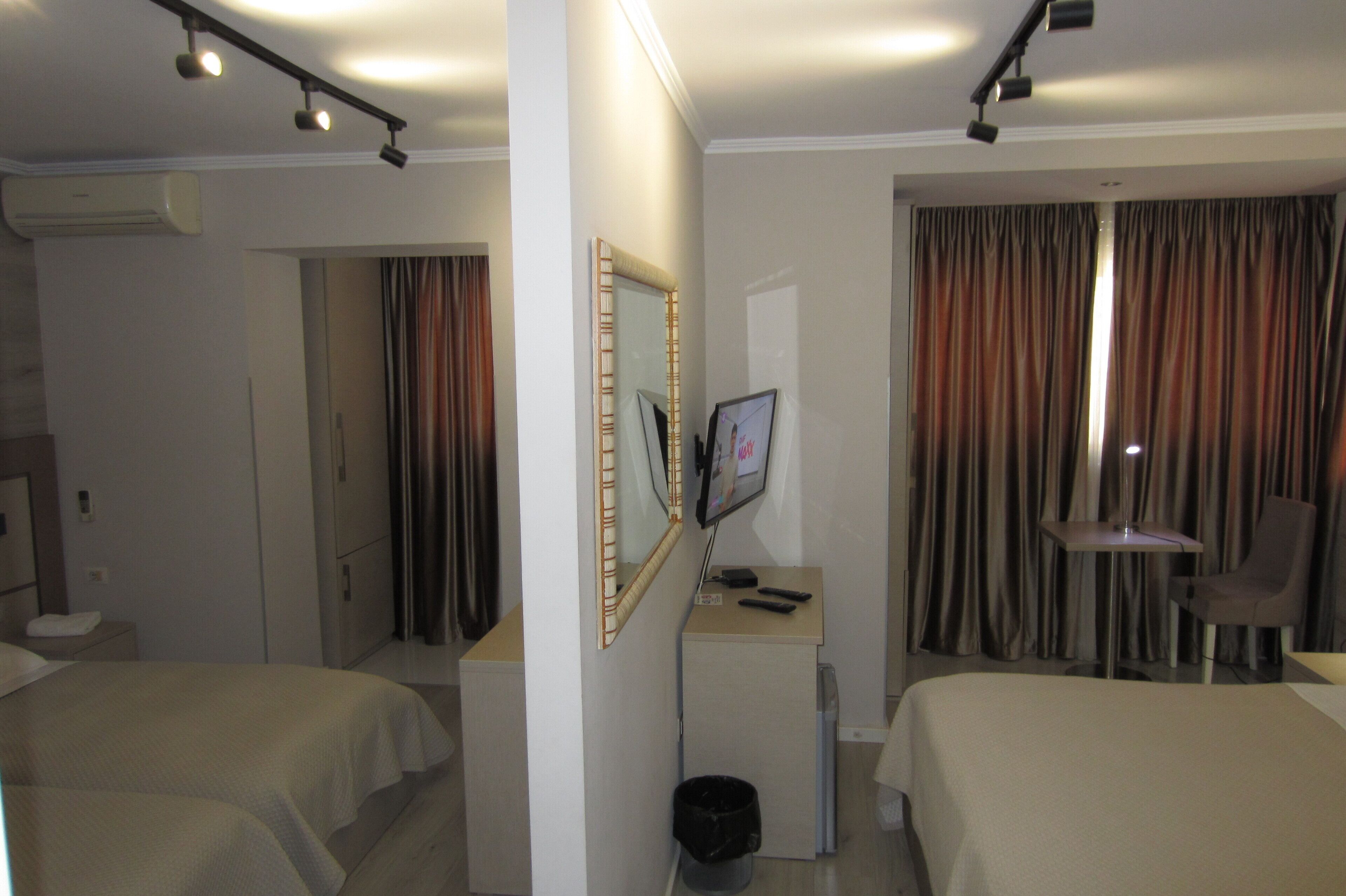 A hotel room with two beds, a desk with a computer, a chair, and a mirror.