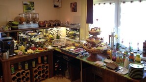 Montaje de bufé con diferentes alimentos y bebidas, una máquina de café y botellas de vino.