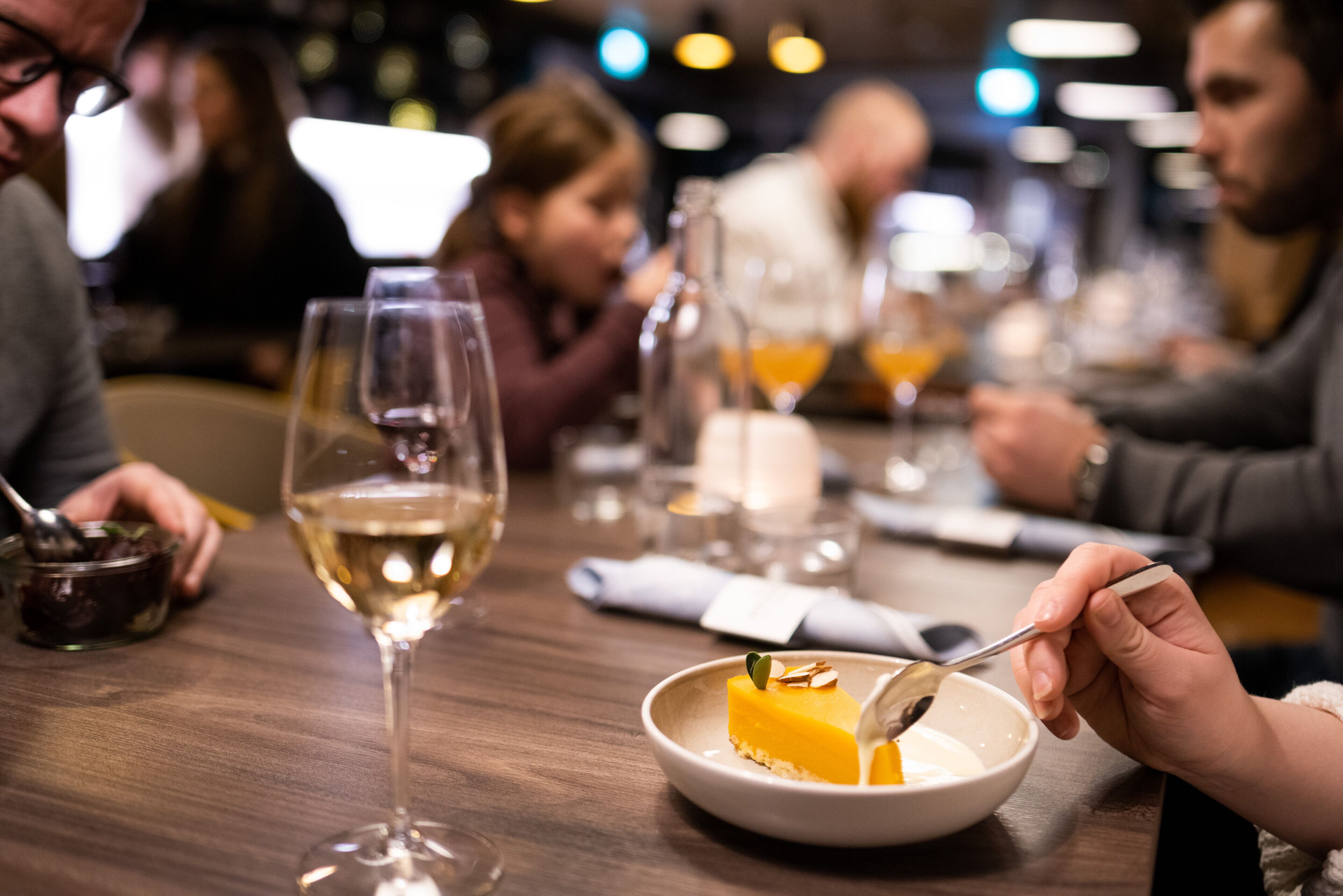 Una mesa de comedor con un plato de postre, una copa de vino y una vela.