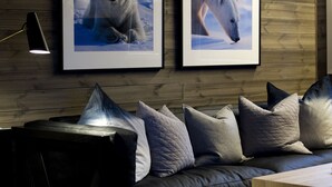 A modern living room with a dark leather sofa, a wooden coffee table, and two framed wildlife photographs on the wall.