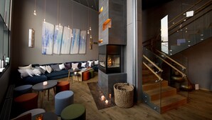 A modern interior with a fireplace, a staircase, and a seating area with a sofa and tables.