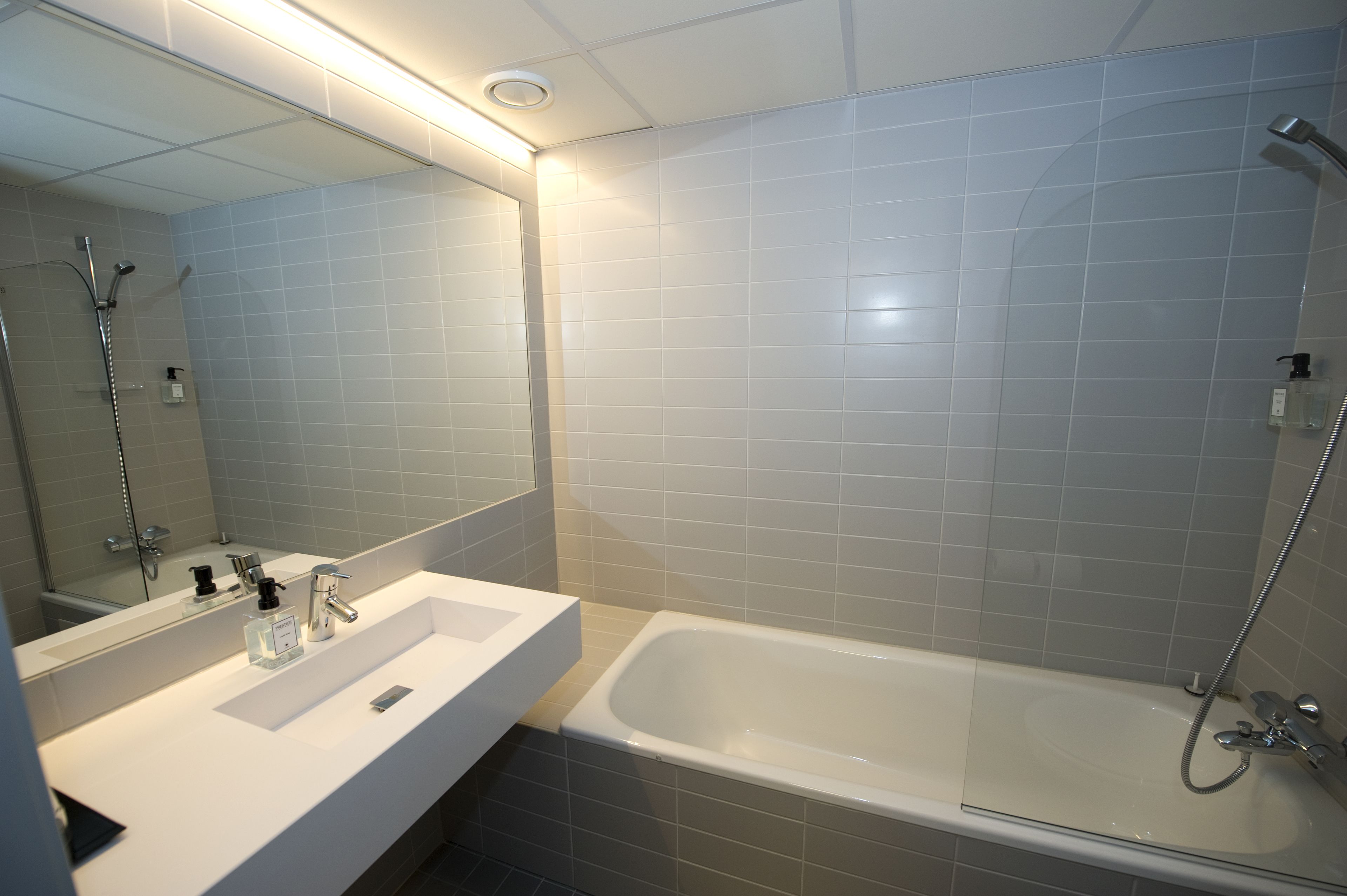 Un baño moderno con un lavamanos blanco, un espejo y una bañera.