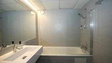 Un bagno moderno con lavandino, specchio e vasca da bagno bianchi.