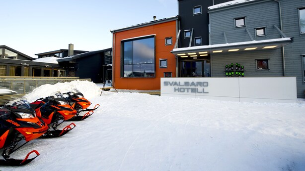 A modern hotel with a large glass window and a sign reading "Svalbard Hotel".