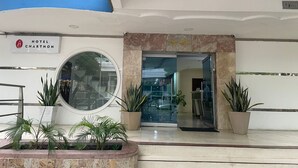 A hotel entrance with a sign reading "HOTEL CHARTHON," a glass door, and potted plants. - Hotel Charthon (Barranquilla)