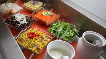Un bufé con diversas opciones de comida, como frijoles, maíz, ensalada y arroz.