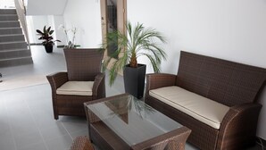A wicker sofa and chairs with a glass coffee table in a modern indoor setting.