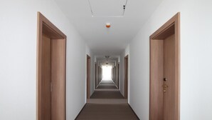 A long, narrow hallway with wooden doors on both sides and a carpeted floor.