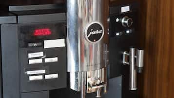 A coffee machine with a cup of coffee being held.
