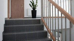 A staircase with a wooden handrail, a potted plant, and a door at the top.