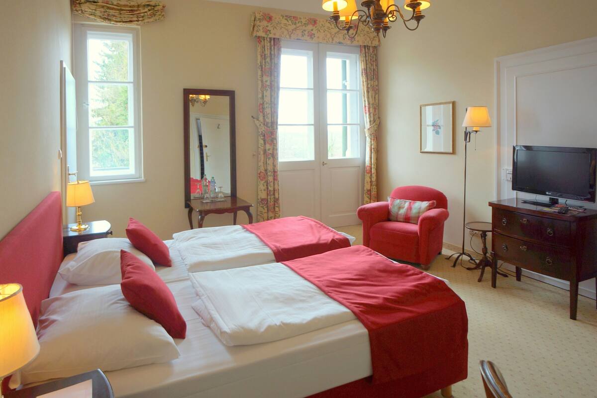A hotel room with two beds, a television, a desk, and a chair.