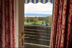 Vista desde un balcón con baranda de madera, cortinas y una puerta.