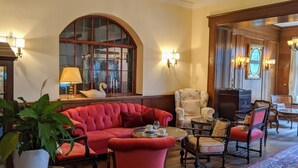 Un hall acogedor con un sofá rojo, una mesa redonda y un amplio ventanal de arco.