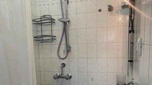 Um banheiro com chuveiro, pia e vaso sanitário.