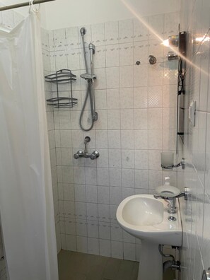 Un baño con ducha, lavabo e inodoro.