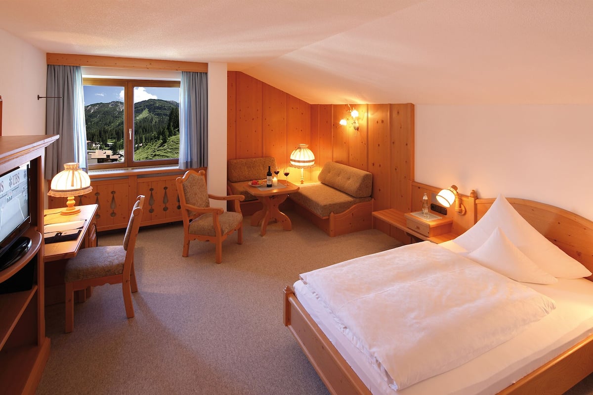 Una habitación de hotel con una cama, un escritorio, una silla, un sofá y un televisor.