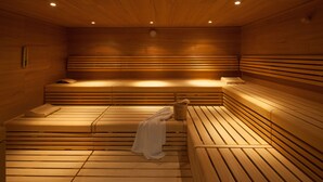 Un sauna avec des bancs en bois et un banc muni d’une serviette.