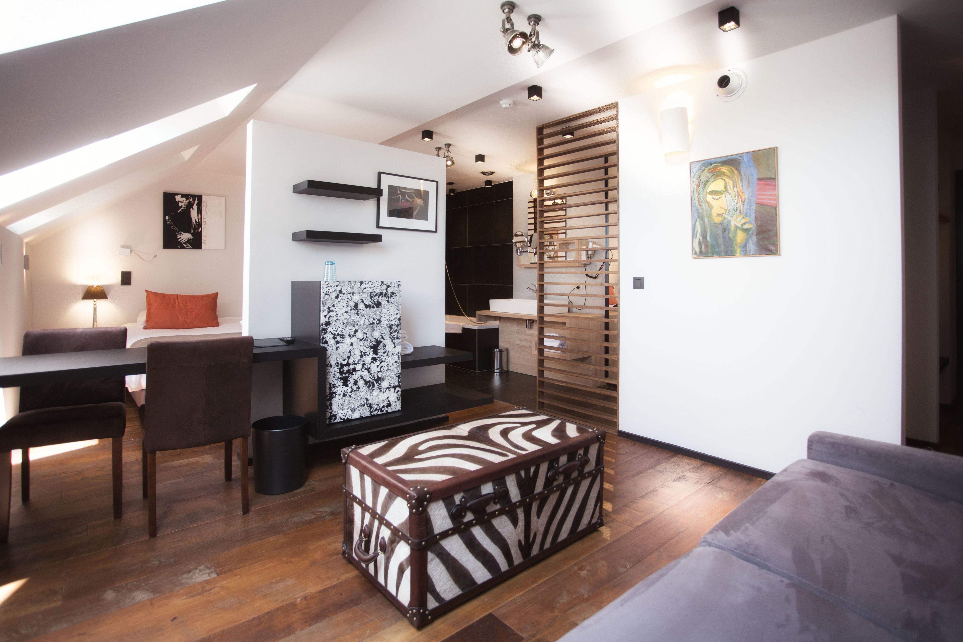 A modern living space with a dining area, a sofa, a zebra-patterned storage box, and artwork on the walls.