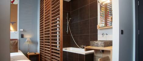 A modern bathroom with a wooden partition, a bathtub, a sink with a stone countertop, and a mirror above the sink.