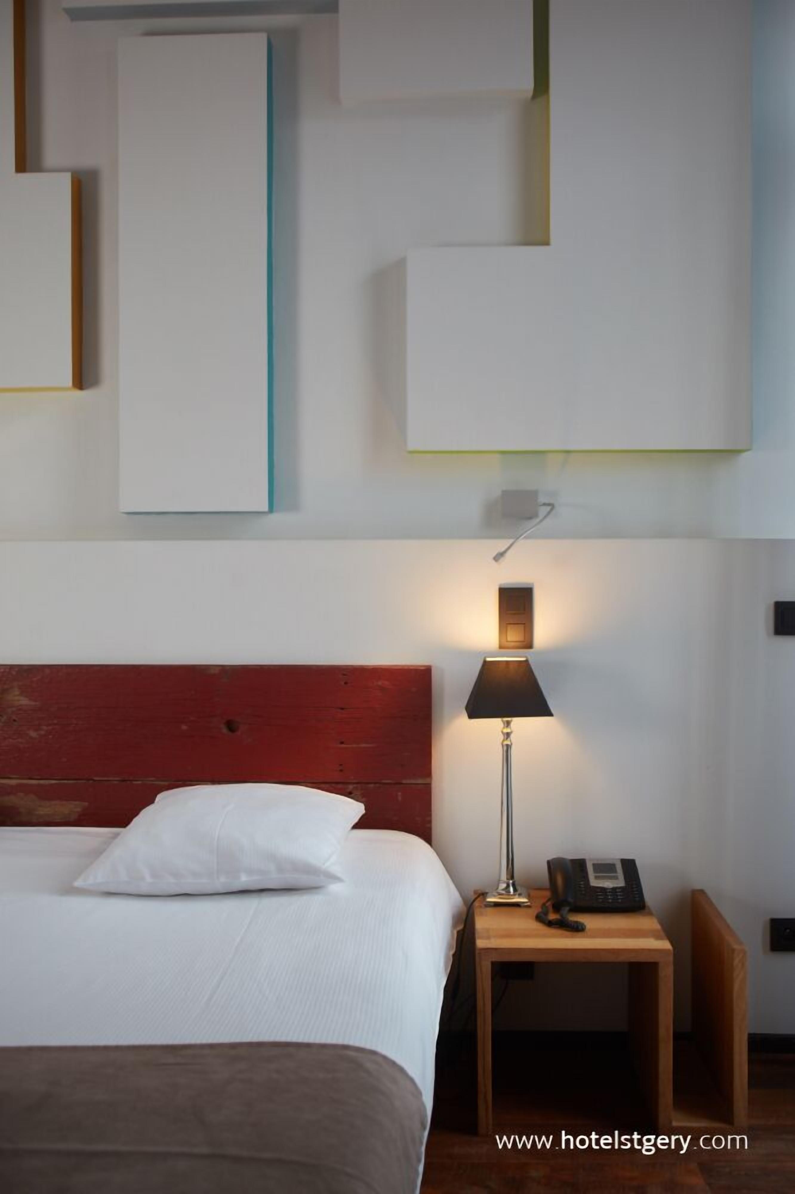 A hotel room with a bed, a nightstand, a lamp, and a telephone.