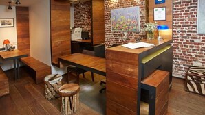 Un restaurant chaleureux avec des tables et des bancs en bois, un mur en briques et un tableau.