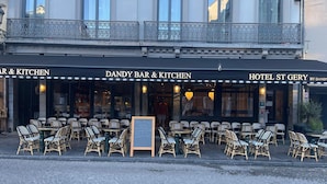 Un restaurant appelé DANDY BAR & KITCHEN, doté d’une terrasse et d’une enseigne indiquant HOTEL ST GERY.