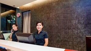 A reception desk with a modern design, featuring a dark textured wall and a window with curtains.