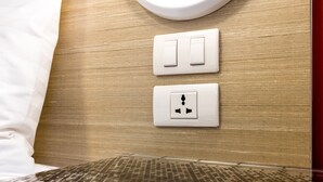A hotel room with a wooden wall, two switches, and a power outlet.