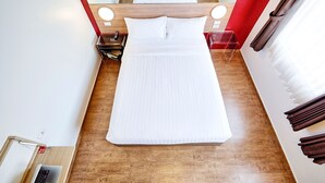 A neatly made bed with white linens, a wooden headboard, and two bedside lamps.