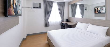 Habitación de hotel moderna con una cama grande, un escritorio, una silla, un televisor de pantalla plana y un espejo.