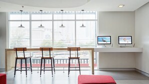 Een moderne kamer met een groot raam, twee monitoren en een rode bank.