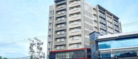 A multi-story hotel with a prominent Red Planet Hotels sign, a modern glass facade, and a visible street view.