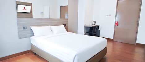 A hotel room with a bed, a desk, a chair, a mirror, and a door.