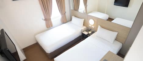A hotel room with two beds, a TV, a desk with a laptop, and a mirror.