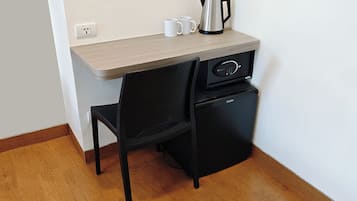 A compact kitchenette with a coffee maker, a small refrigerator, and a chair.