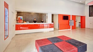A modern reception area with a red and white color scheme, a reception desk, and a seating area with red and grey cushions. - Easy Planet Hat Yai (Hat Yai)
