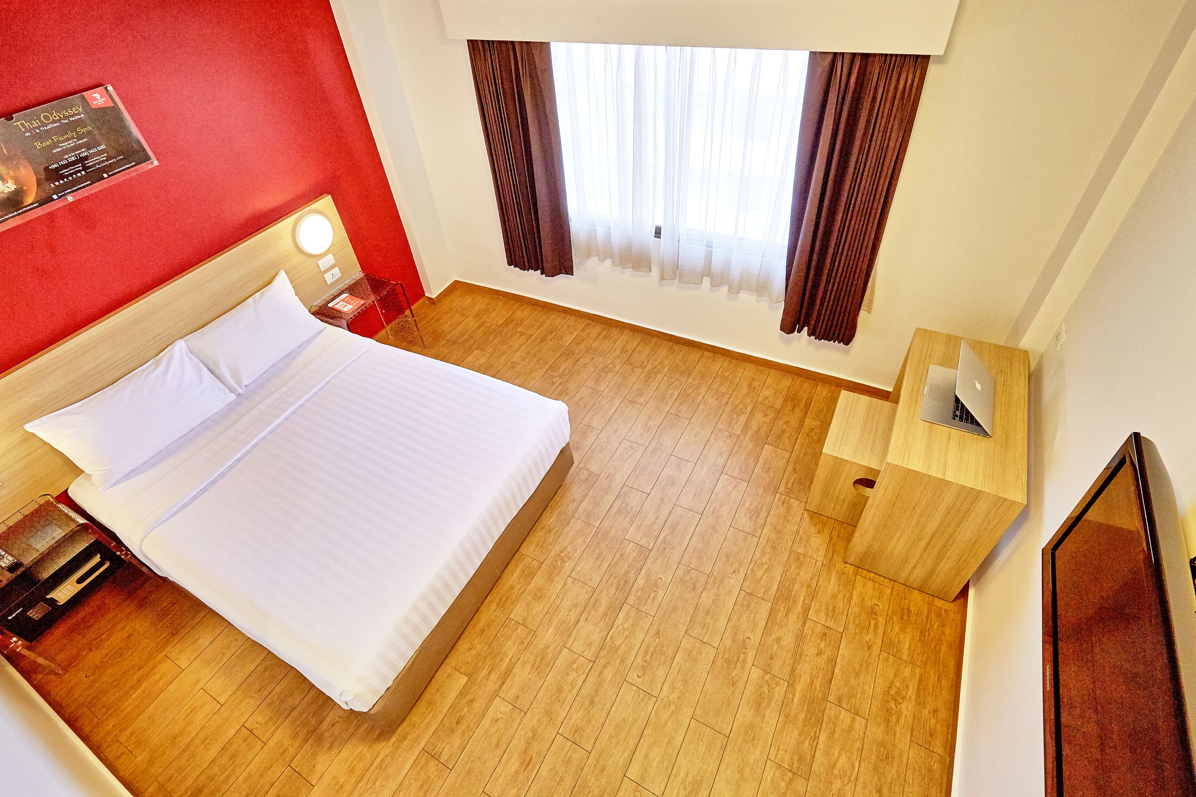 Ein Hotelzimmer mit Bett, Schreibtisch und einem fensterbepflanzten Fenster.
