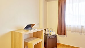 A hotel room with a wooden desk, a laptop, a coffee maker, and a minibar. - Easy Planet Hat Yai (Hat Yai)
