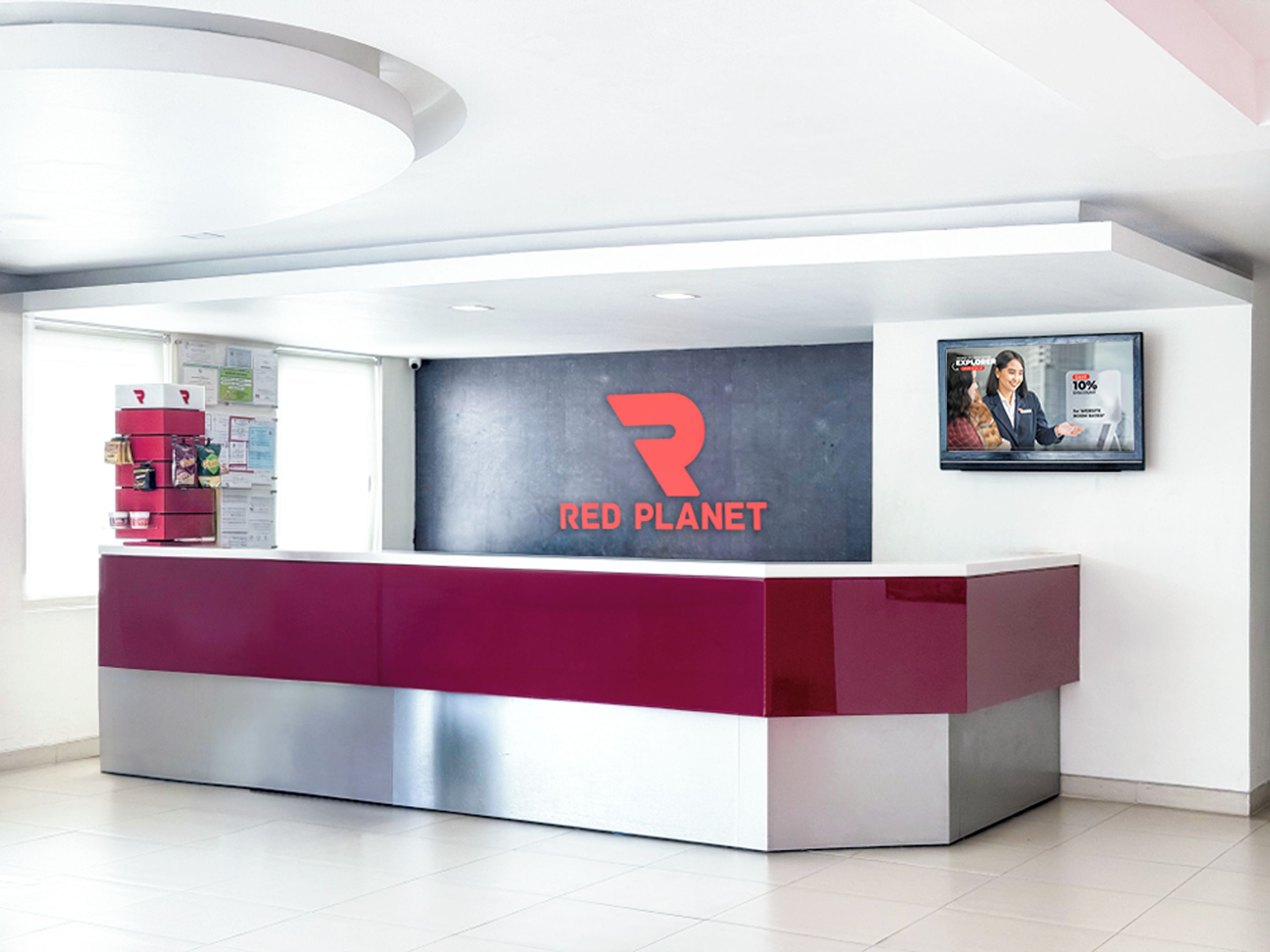 Un comptoir d’accueil moderne, agrémenté d’un logo, d’un écran numérique et d’un tableau encadré accroché au mur.