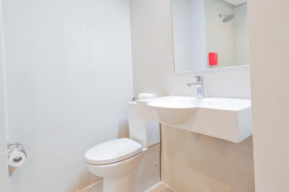 Une salle de bain comprenant des toilettes, un lavabo, un miroir et un espace douche.