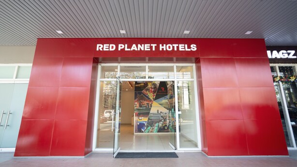 Exterior del hotel Red Planet, con fachada roja y entrada de vidrio.