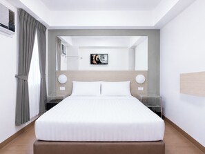 Une chambre d’hôtel moderne avec un grand lit, des tables de chevet, une télévision et un miroir.