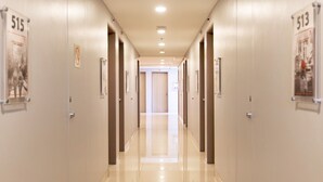 Un pasillo con puertas numeradas 515 y 513, que conduce a una habitación con una puerta al final.