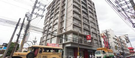 Un edificio de varios pisos con una planta baja comercial, que incluye un restaurante Red Planet y una tienda Sapa Bato.